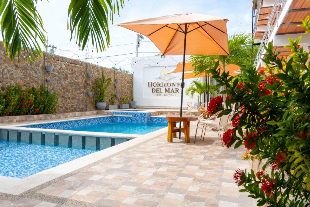a pool with an umbrella and chairs and a table with at Horizonte del Mar Hotel Boutique in Santa Marta