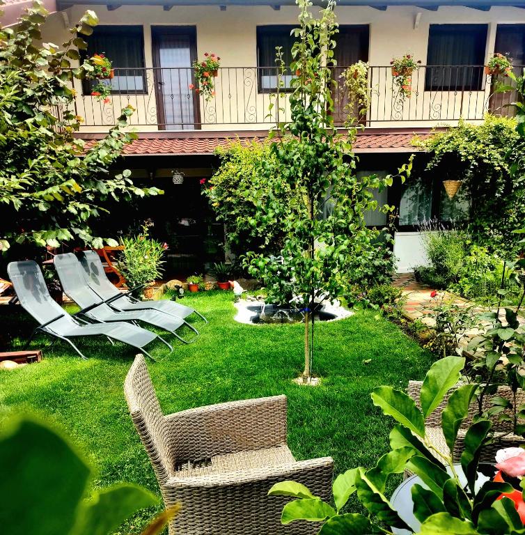 a garden with chairs and a tree and a building at Casa Narciselor in Râşnov