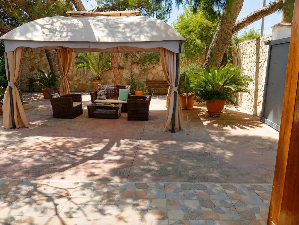 a patio with an umbrella and chairs and a table at Marea Blanca - Rooms & Garden in Torre Lapillo