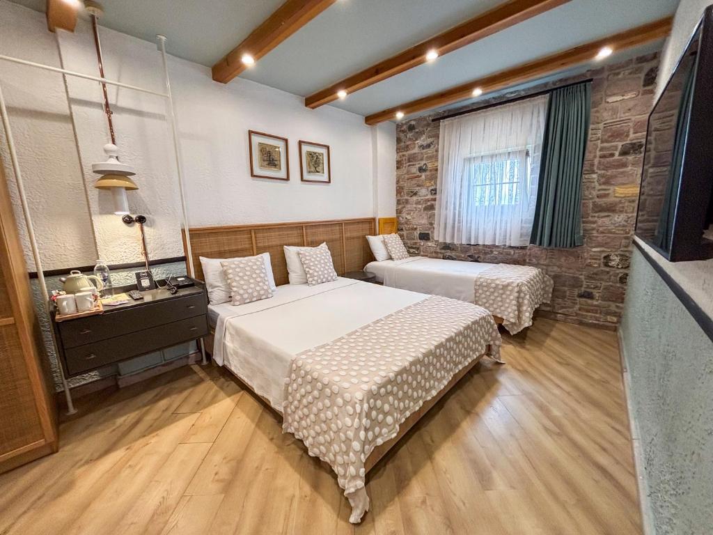 a bedroom with two beds and a television in it at Qara Otel in Ayvalık