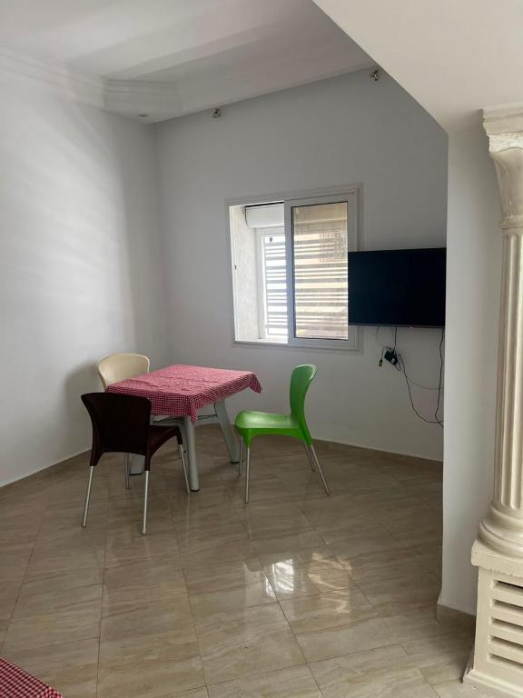 a dining room with a pink table and green chairs at Dar El corniche in Mahdia