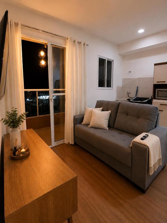 a living room with a couch and a table at Flat Terras de Portinari in Barretos