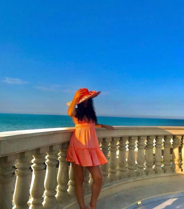 a woman standing on a balcony looking at the ocean at Caspian Seaside Hotel in Sumqayıt