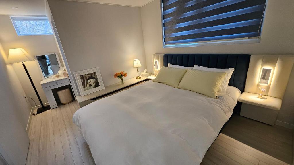 a bedroom with a large white bed and a window at 대구 수성구 행복의집 
