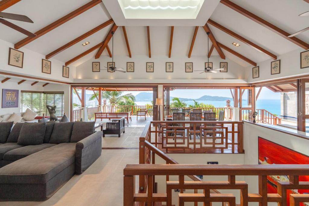 a living room with a couch and tables and windows at Patong 4BR Seaview Villa with Infinity Pool in Patong Beach