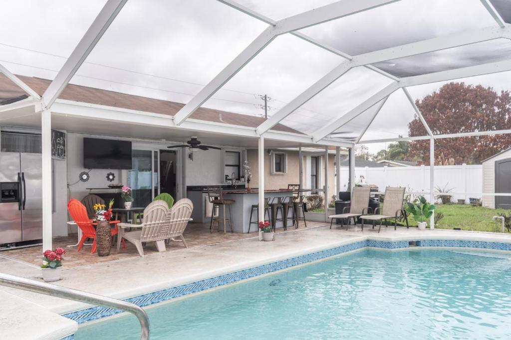 a patio with a swimming pool and a white umbrella at Port St Lucie Poolside Oasis in Port Saint Lucie