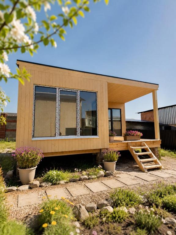 a tiny house with a porch and some plants at EL House in Karakol