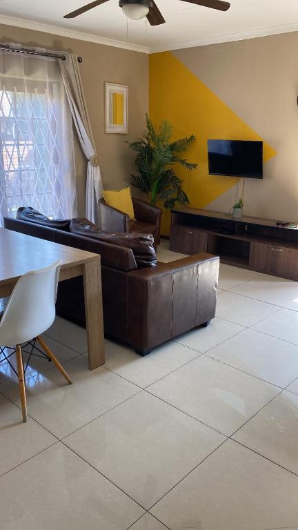 a living room with a leather couch and a tv at Tumi's Home away- 3 Bedroom in eMalahleni
