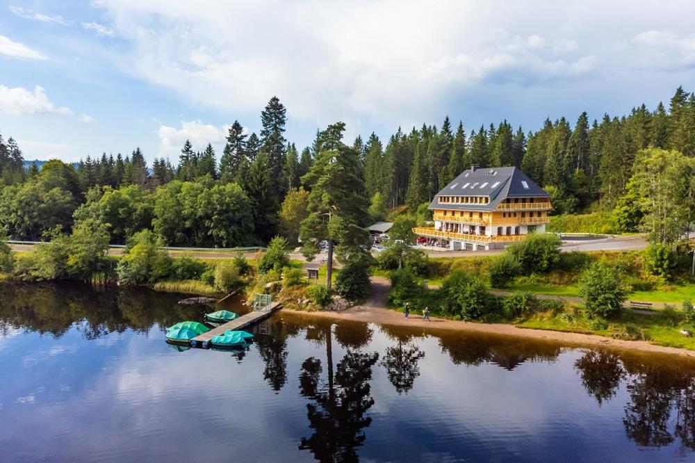 a house on a river with a boat in the water at Köhlerei am See in Feldberg