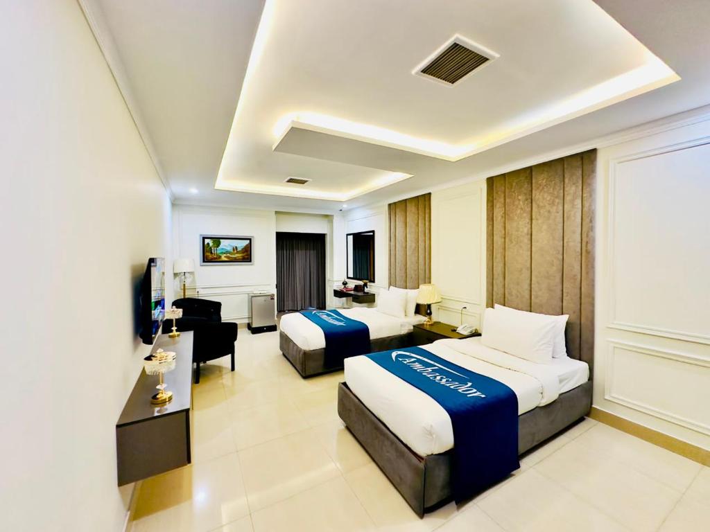 a hotel room with two beds and a living room at Ambassador Hotel in Lahore