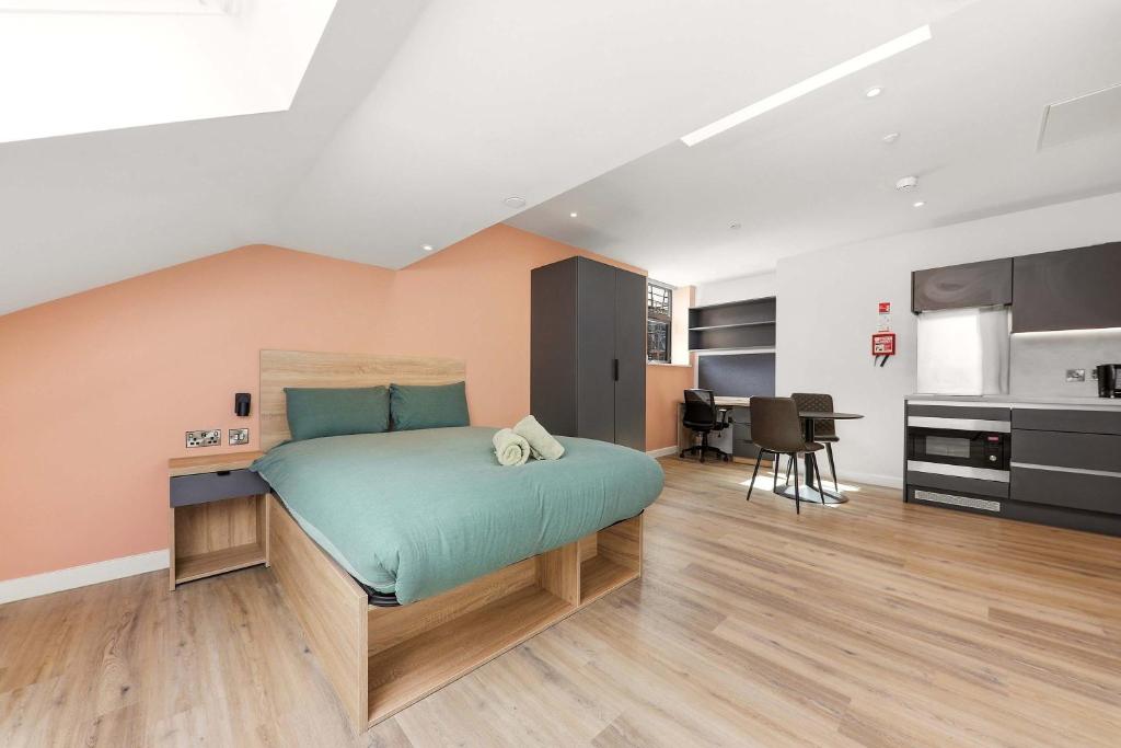 a bedroom with a bed with a desk and a kitchen at Modern Studio in Central Leeds in Leeds