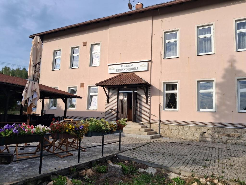 a building with a umbrella and flowers in front of it at Penzion Krušnohorka in Tatrovice