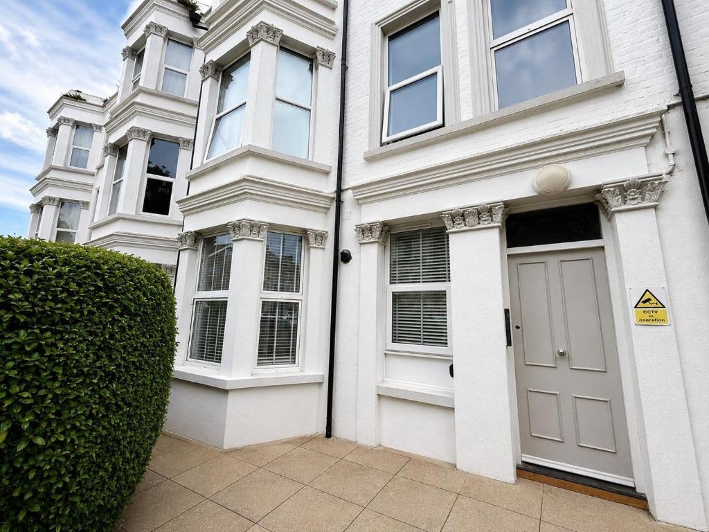 a white house with a door and a hedge at Number 6 in Margate