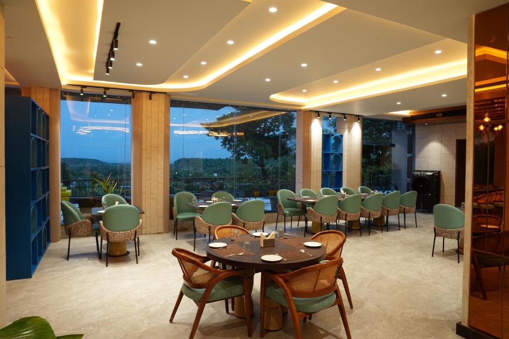 a restaurant with tables and chairs and a large window at Mayur baag resort in Sāgar