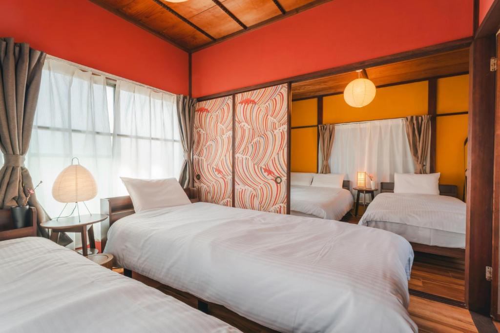 two beds in a room with red walls at Odawara Nautical Nook in Odawara