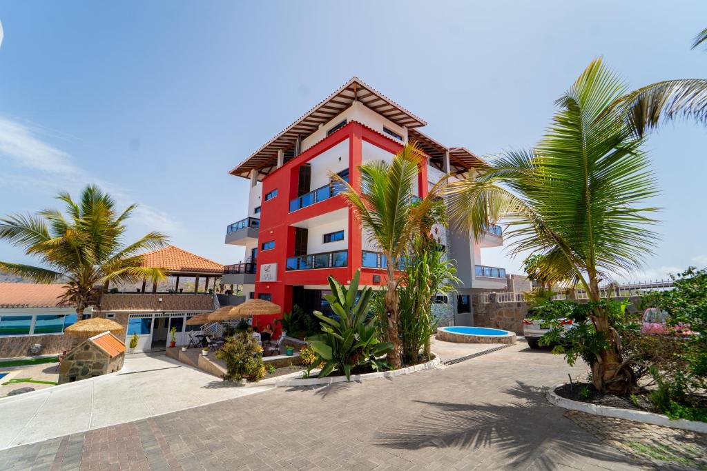 a red building with palm trees in front of it at Hotel Cantinho in Montanha