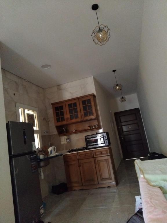 a kitchen with wooden cabinets and a black refrigerator at Cozy studio in sahel in El Alamein
