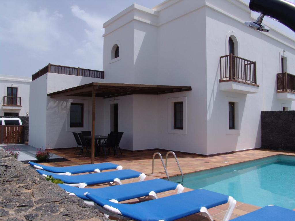 a group of blue lounge chairs next to a swimming pool at Casa Fama con piscina privada clima in Yaiza