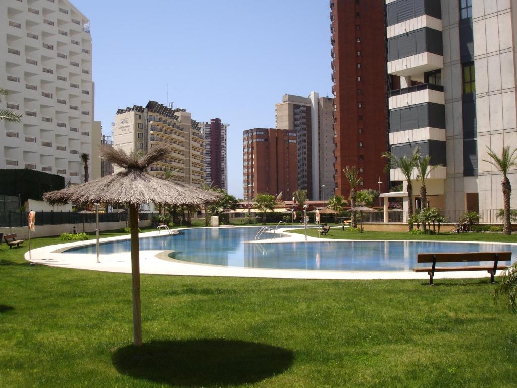 a large swimming pool with a bench and an umbrella at Gemelos 26 - Zand Properties in Benidorm