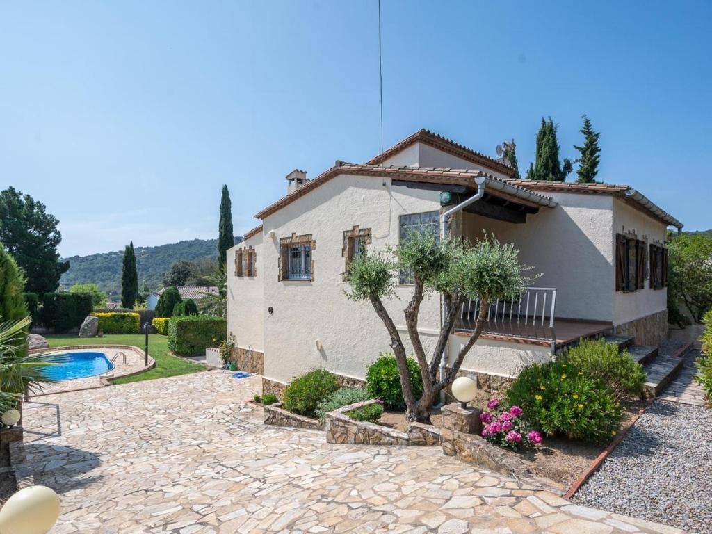 a house with a garden and a swimming pool at Villa Las Dos Rocas in Calonge