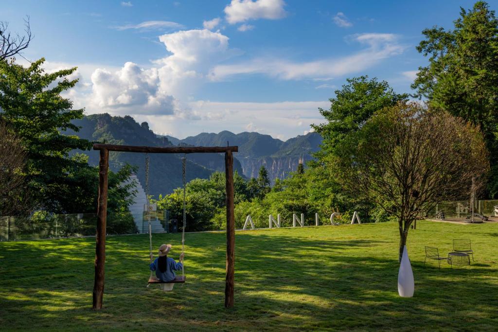 a woman sitting on a swing in a park at Pandora Annica Villa in Zhangjiajie