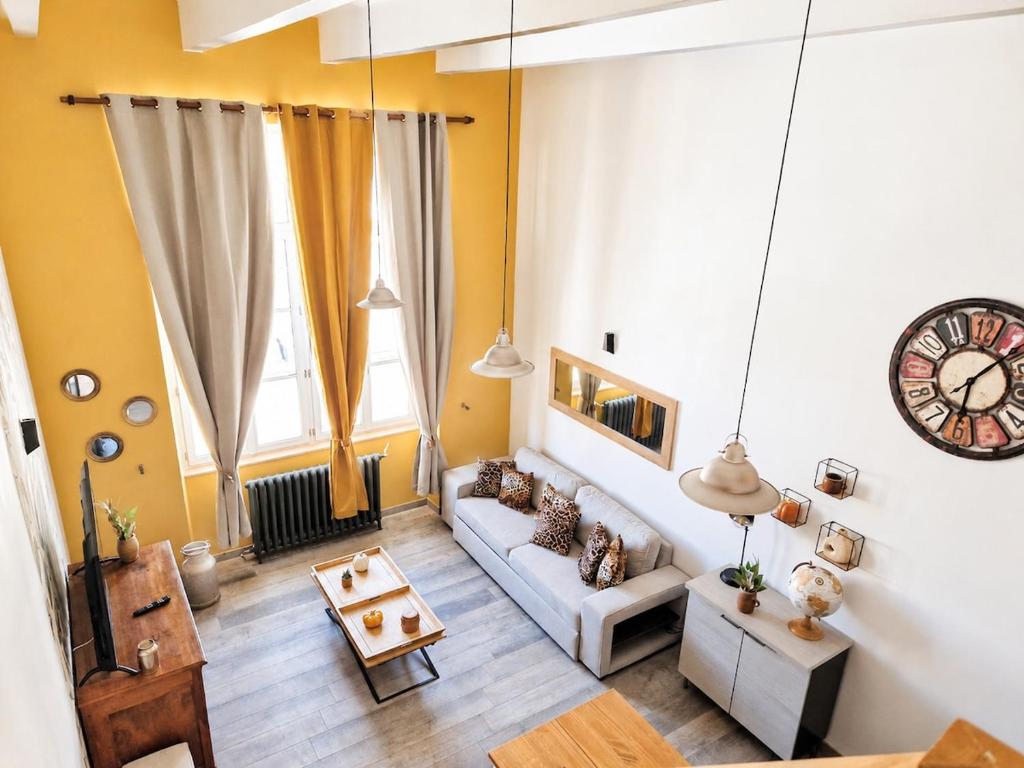 a living room with a couch and a clock on the wall at Retro Chic in Saumur