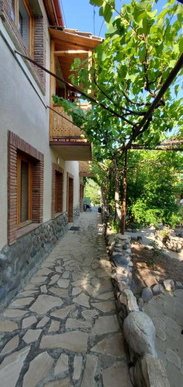 a stone walkway next to a building with a tree at Mtskheta Pool and Veranda in Tsitsamuri