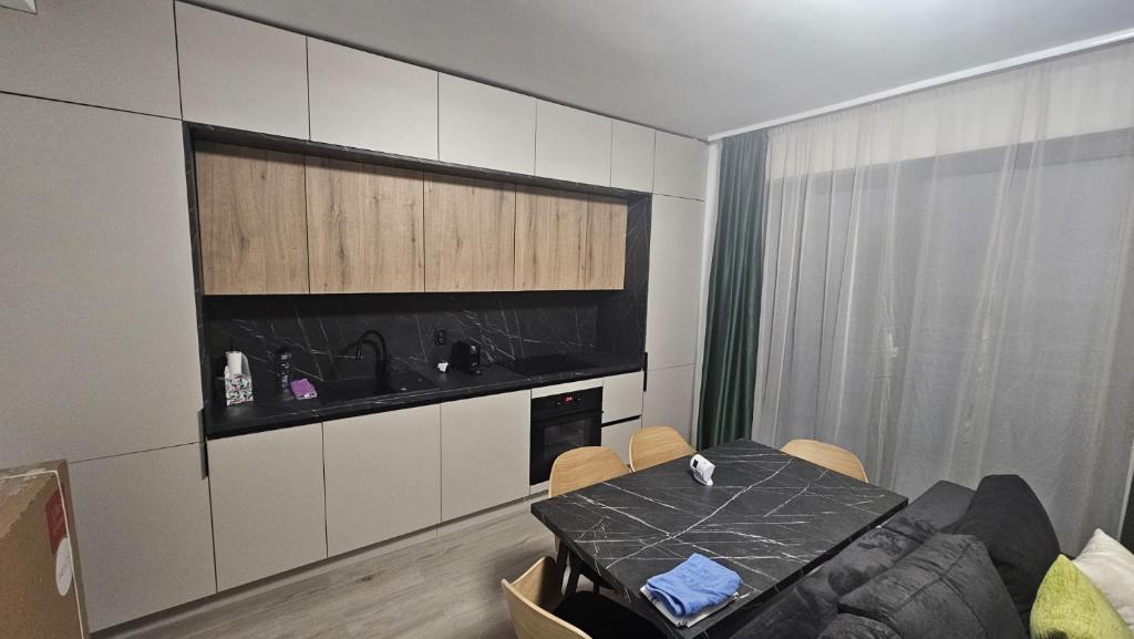a living room with a table and a kitchen at Donath park view in Baciu