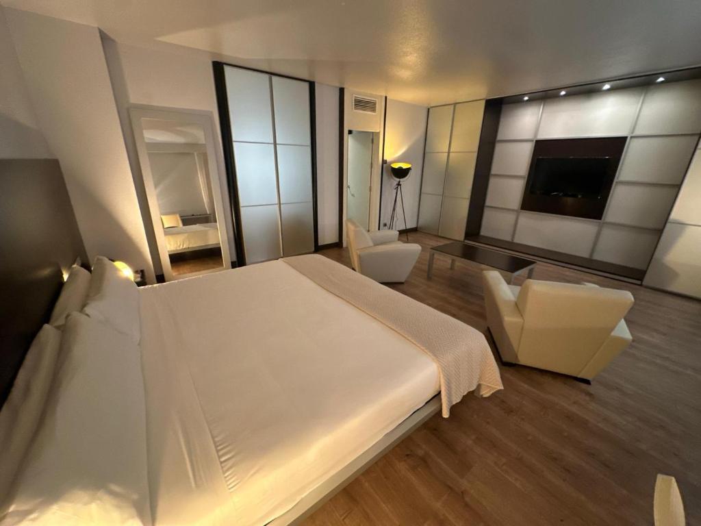 a bedroom with a large white bed and two chairs at Puerta de Africa in Ceuta