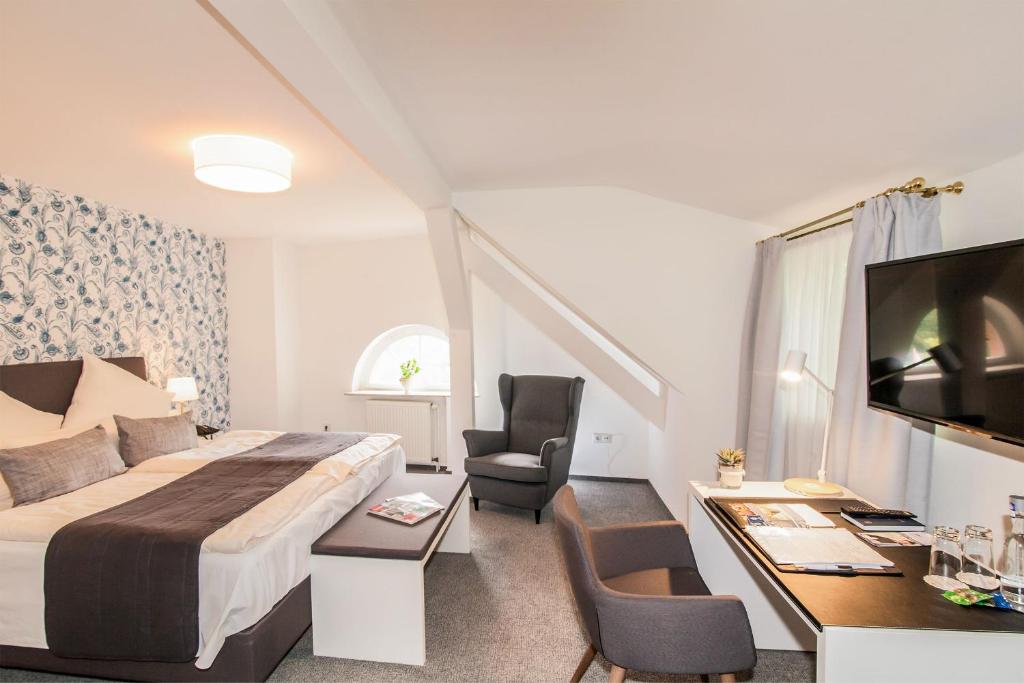 a hotel room with a bed and a desk and a tv at Hofgut Dippelshof Hotel- und Restaurant KG in Darmstadt