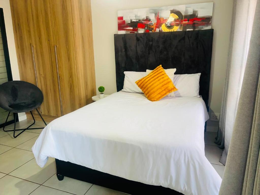 a bedroom with a bed with a orange pillow on it at Cozy&Pristine The Blyde in Pretoria