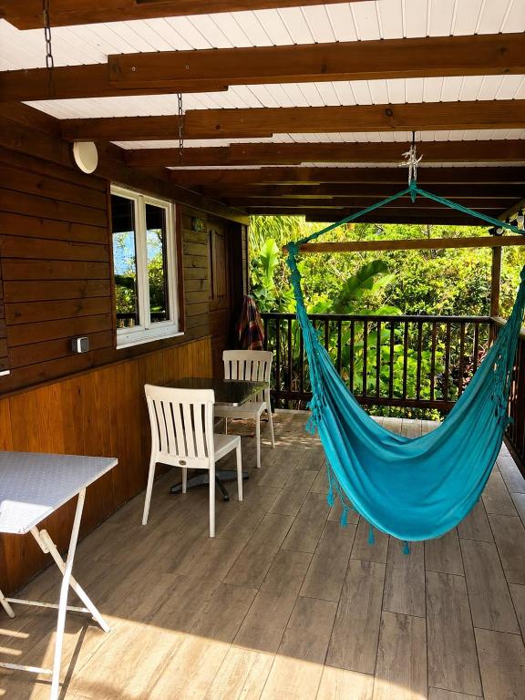 a hammock on the back porch of a cabin at Gîte Bananier - Villa Marina in Bouillante