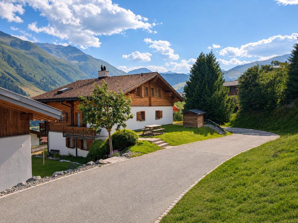 a house on a hill next to a road at Maisonette-Wohnung in Rueras bei Sedrun - 200m zum Bahnhof - Perfekt für Ski & Ausflüge in Rueras