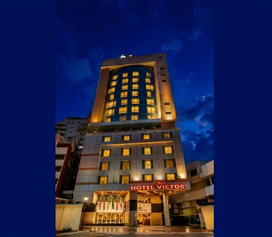 a hotel building with a hotel sign lit up at night at Hotel Victory - Best in City Center in Dhaka