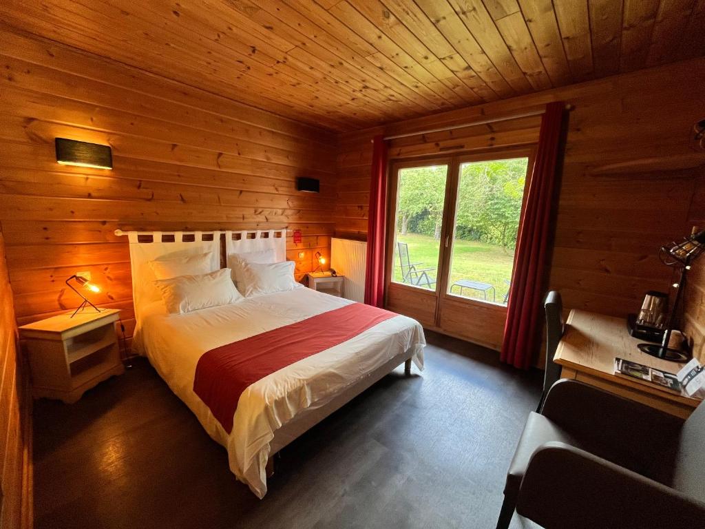 a bedroom with a bed in a wooden room with a window at Logis - Hôtel & restaurant Les Trois Fontaines in Marconne