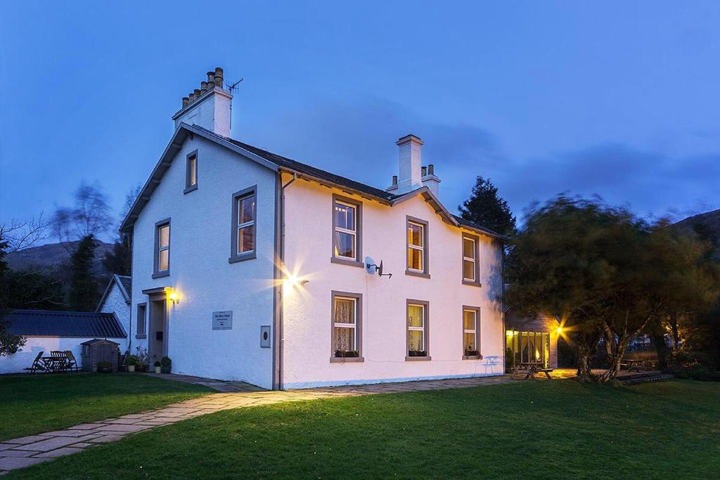 a large white house sitting on top of a lush green field at The Shore House in Lochgoilhead