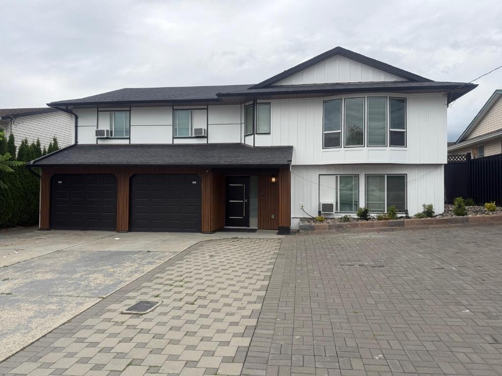 a white house with a garage and a driveway at J & J Dream Villa Ltd in Abbotsford