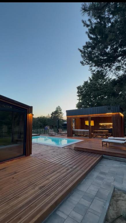 a wooden deck with a pool and a house at Villa Ruj Retreat Deliblatska Peščara in Šumarak