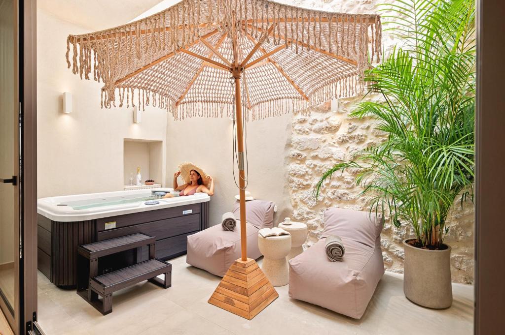 a woman sitting in a bathroom with an umbrella at Asikiko Suites in Rethymno