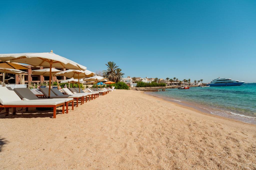 a beach with chairs and umbrellas and a cruise ship at Aqua Fun Resort in Hurghada