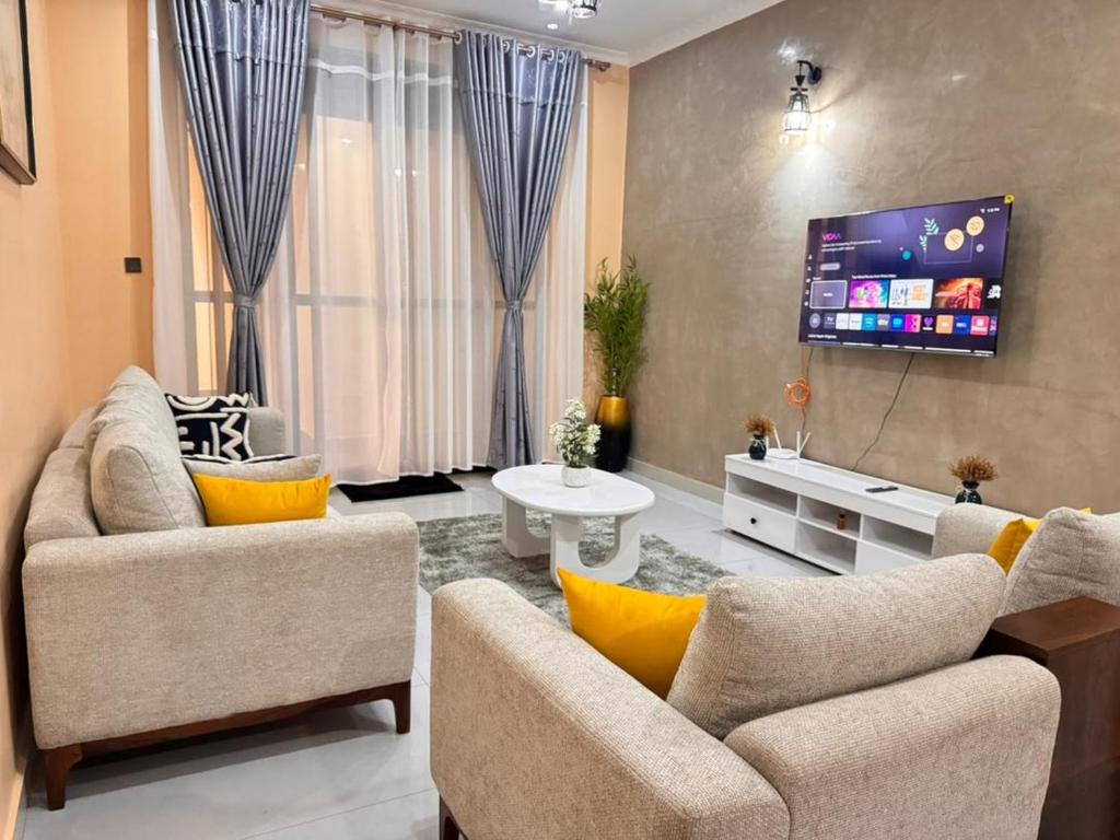 a living room with two couches and a flat screen tv at Mallony Homes in Kampala