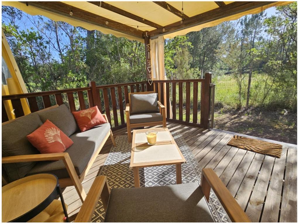 a porch with a couch and chairs on a deck at Camping LES ARBOUSIERS Carcans in Carcans