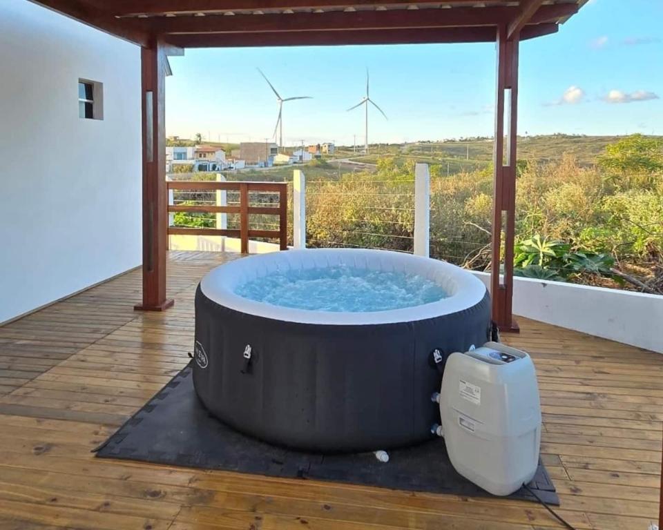 a hot tub on a deck with wind turbines in the background at Jacuzzi Privativa, Chalé Romântico com Decoração in Monte das Gameleiras