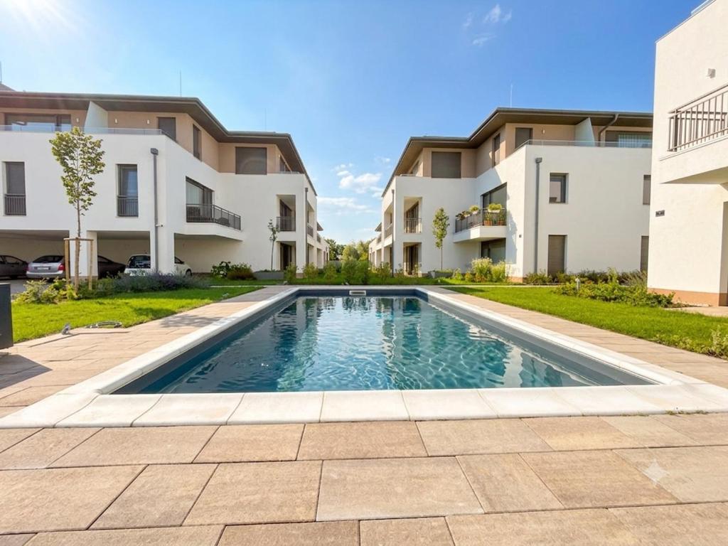 a swimming pool in front of two apartment buildings at Anna Lakeside Apartman in Gárdony