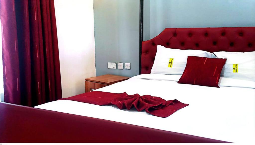 a bed with a red headboard and white sheets and red pillows at Toquee Hotel Bookings - Nairobi in Nairobi