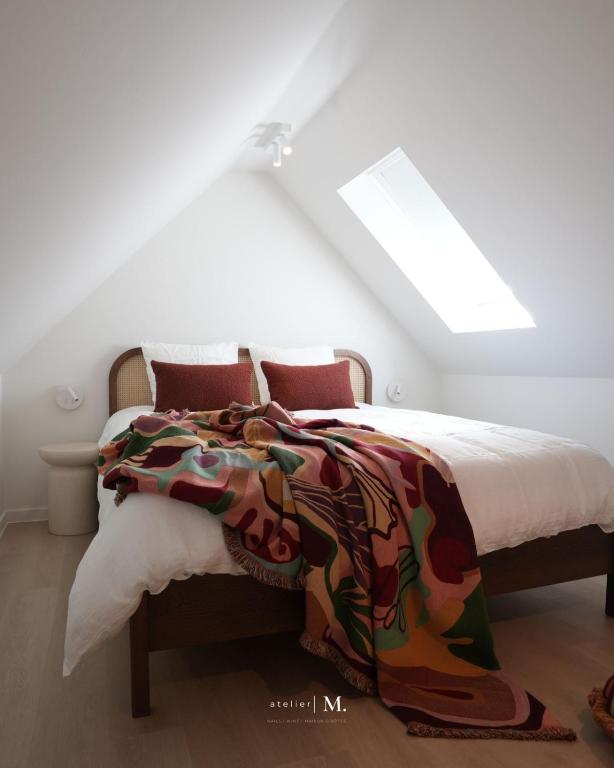 a bedroom with a bed with a colorful blanket on it at Atelier M in Kruisem