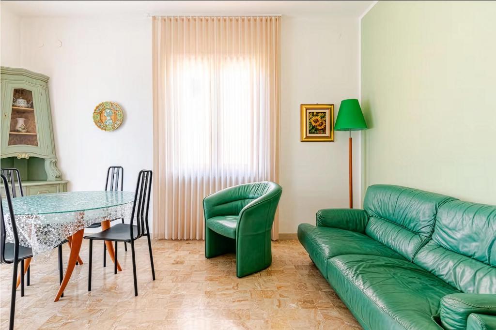 a living room with a green couch and a table at Apartment Superiore a 950 metri dal mare in Albisola Superiore