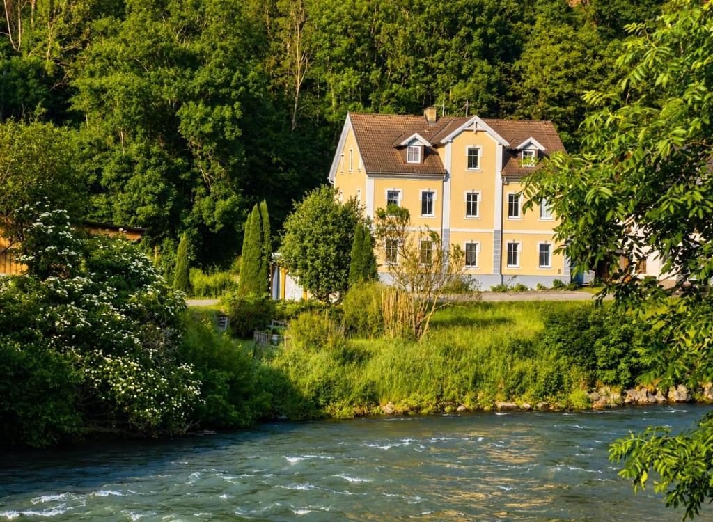 a large yellow house next to a river at Apartment Gletscher & Fluß in Penk