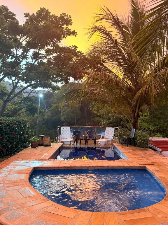 a pool with a table and chairs in a yard at Moon Wind Tayrona Hostel in El Zaino