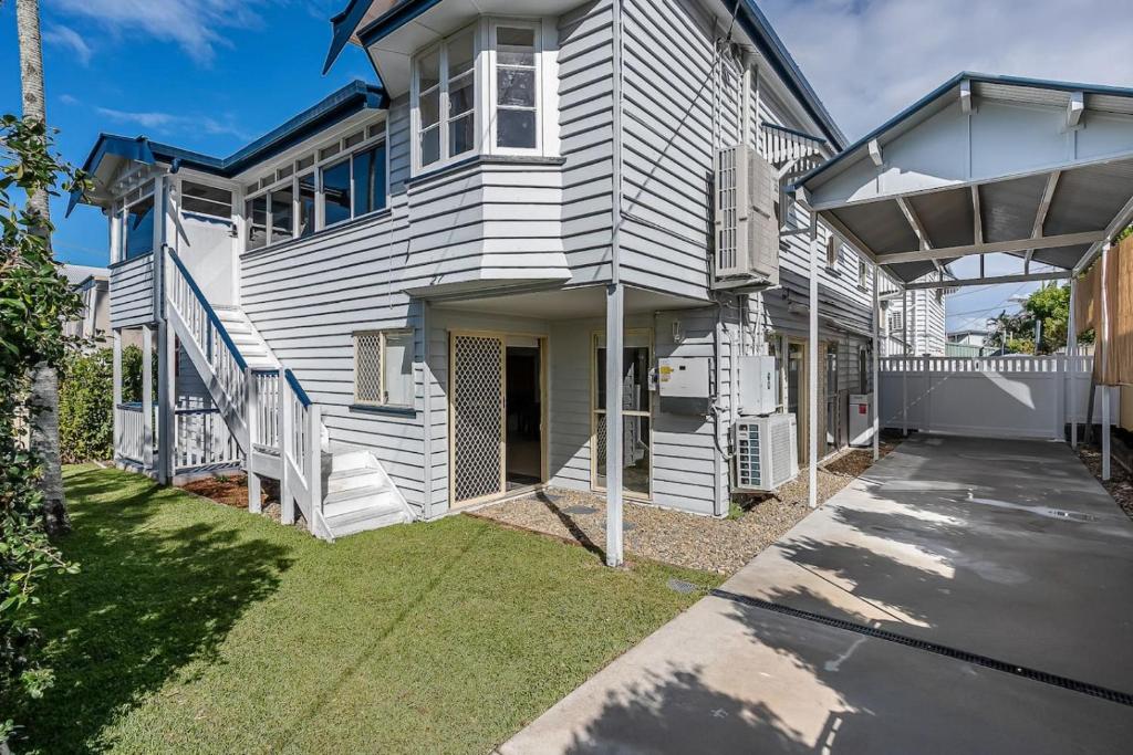 a white house with a porch and a driveway at The Palms in Redcliffe